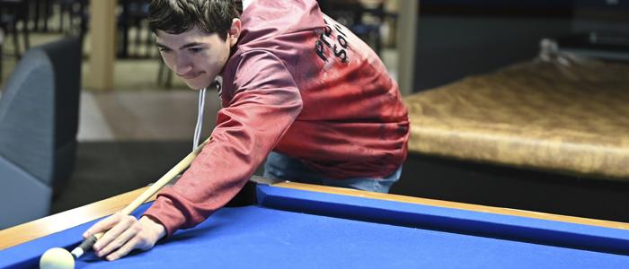A student plays pool on campus.